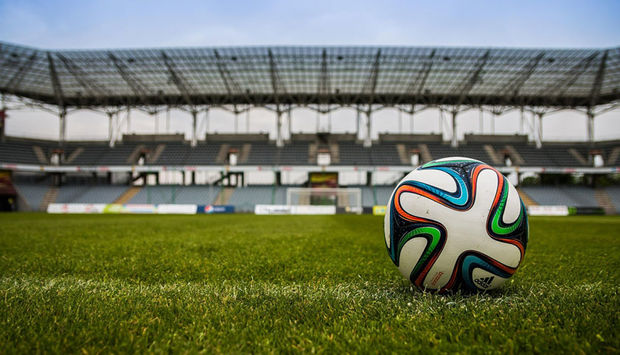 Ein Fußball liegt auf dem Rasen in einem großen Fußballstadion