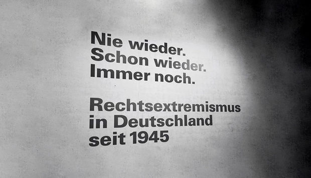 Schräge schwarze Aufschrift "Nie wieder. Schon wieder. Immer noch. Rechtsextremismus in Deutschland seit 1945"mit Schattenwurf 