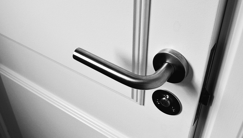 Eine fast geschlossene weiße Holztür. Sie kann für erschwerten Zugang zu Antidiskriminierungsberatung stehen. 