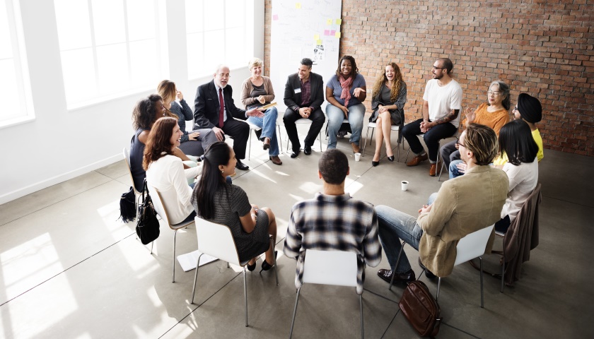 Eine Gruppe von Menschen sitzt in einem Stuhlkreis bei einem Workshop.